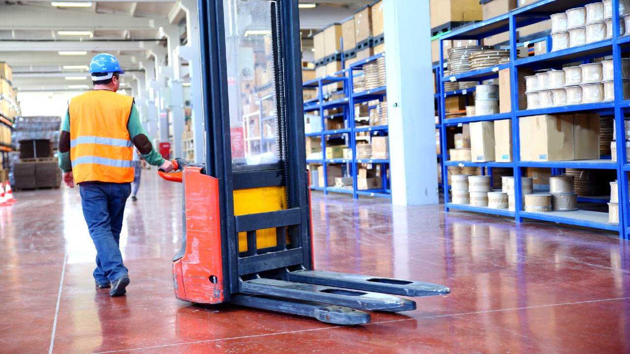 A worker moving a forklift in a warehouse.