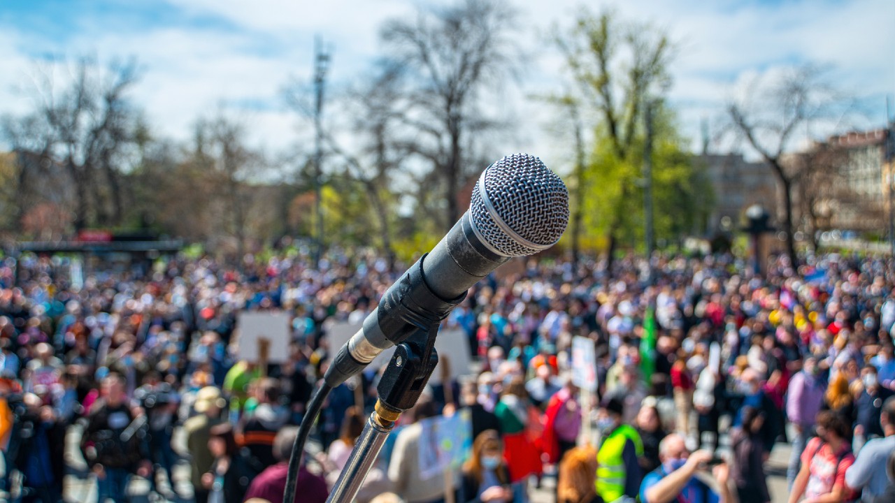 Photo of microphone in front of crowd of people.