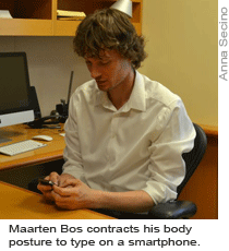Maarten Bos contracts his body posture to type on a smartphone.