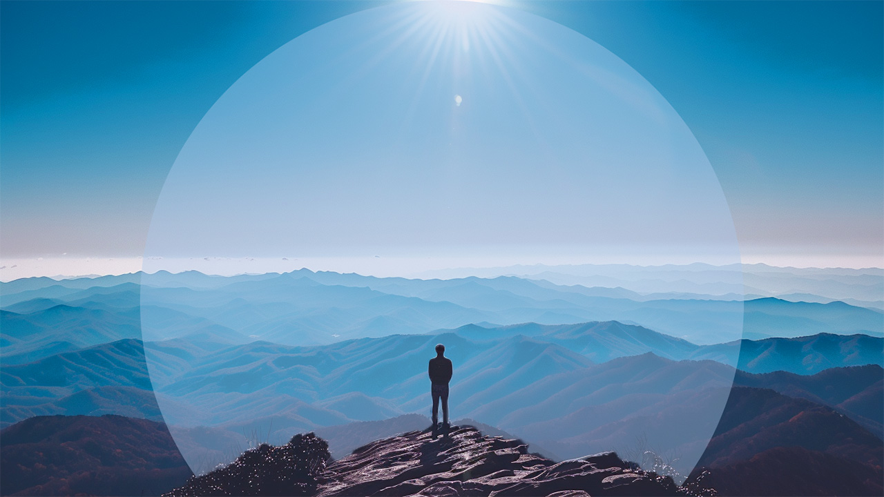 Image of person standing on mountain looking out at view.